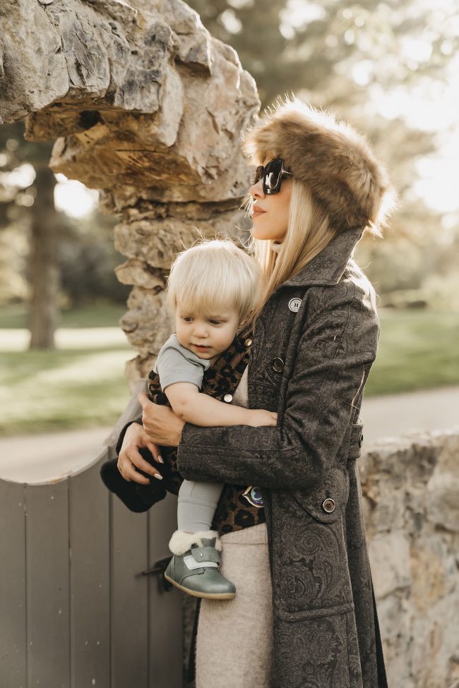 Fashion blogger wearing a fur hooded coat and baby wearing Rags clothing